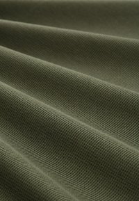 Tkany materiał w oliwkowej zieleni, z prążkowanym wzorem i subtelnym połyskiem. Materiał wydaje się miękki i elastyczny, z delikatnymi fałdami.