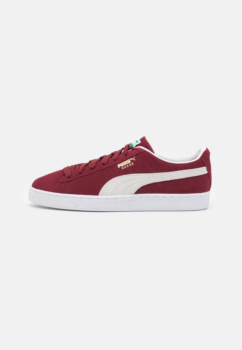 Red suede sneaker with white leather accents, flat white rubber sole, rounded toe, and textured finish. Features gold logo on side.