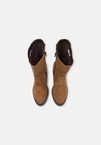 Bottes en suède marron à mi-mollet avec une finition légèrement texturée, dotées d'une fermeture éclair sur le côté et d'une semelle en caoutchouc lisse.