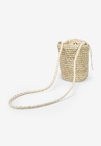Borsa a secchio in paglia intrecciata beige con tracolla intrecciata e chiusura a cordoncino in tessuto morbido. La superficie testurizzata aggiunge dimensione.