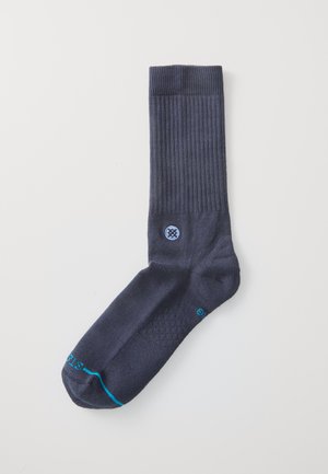 Navy crew sock with ribbed texture and diamond pattern on footbed. Features blue accent on toe and logo near the ankle. Soft fabric.