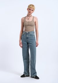 Beige ribbed tank top paired with high-waisted light blue denim jeans. The jeans are wide-leg with a straight fit and classic five-pocket design.