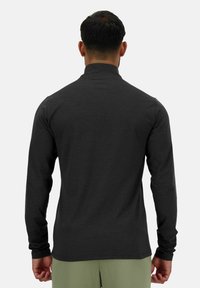 Chemise à manches longues en tissu gris foncé avec un col montant, une silhouette ajustée et des épaules sans couture. Présente une texture lisse et un design minimaliste.