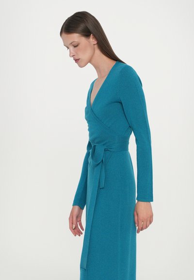 Turkos omlottsklänning i mjukt tyg med långa ärmar, djup v-ringning och knytbart midjeband för justerbar passform.