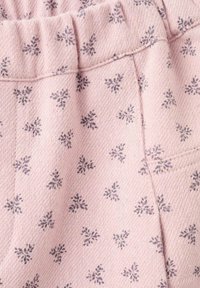 Rosa strukturerad tyg med ett subtilt blommönster i mörkgrått. Har en elastisk midja och sidofickor.