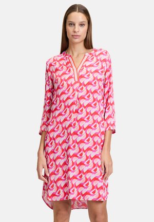 Rosa Tunika-Kleid mit geometrischem Muster in verschiedenen Rosatönen und Weiß, V-Ausschnitt und Dreiviertelärmeln.