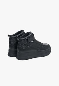 Czarne wysokie trampki wykonane z leatheru o teksturowanym wykończeniu, z miękkim kołnierzem i masywną gumową podeszwą. Posiadają zapięcie na klamrę oraz sznurowanie.