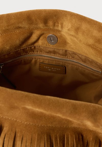 Interno di una borsa in suede marrone con una tasca con zip, chiusura a scatto in ottone e un'etichetta con la scritta "Tory Burch New York." Tessuto liscio e fodera morbida.