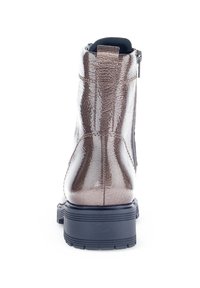 Botte chelsea en métal brun avec une finition texturée, semelle en caoutchouc noir et fermeture éclair sur le côté. Dispose d'un col rembourré pour plus de confort.