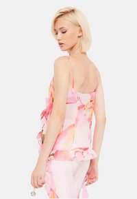 Top senza maniche con motivo floreale in tessuto rosa chiaro, con un orlo a balze. Presenta spalline sottili e una vestibilità ampia.