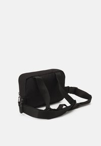 Borsa in tessuto nero con forma rettangolare, due manici, tracolla regolabile e chiusura con zip. Texture liscia con dettagli minimi.