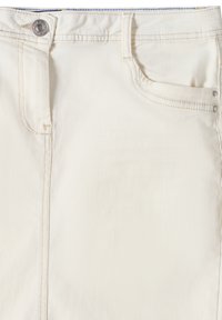 Jupe en denim blanc avec une fermeture à boutons sur le devant, des passants de ceinture et des poches standard. Le tissu a une texture lisse avec des détails de coutures visibles.