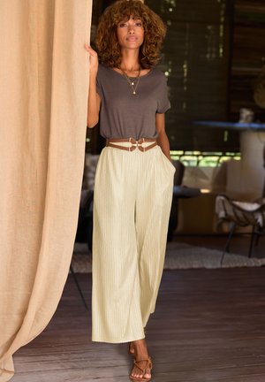 Gray short-sleeve top, wide light yellow pleated pants, brown belt with decorative buckle, and brown sandals. Indoor setting with soft lighting.