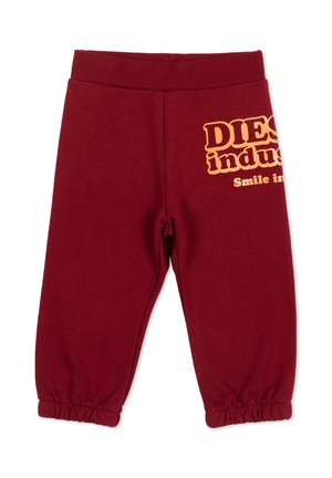 Pantaloni bordeaux per bambini piccoli con vita e polsini elastici, con testo giallo parziale "Diesel industry Smile in" sulla coscia destra.