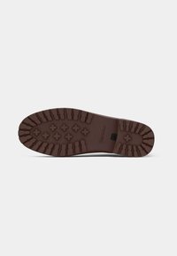 Bruine rubberen zool met een patroon van groeven en verhoogde accenten voor grip; beschikt over een logo dat nabij het hielgebied is geperst.