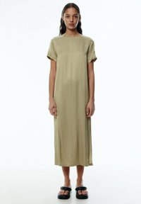 Olivgrünes Midikleid mit geradem Schnitt, kurzen umgeschlagenen Ärmeln und seitlichen Schlitzen, gefertigt aus weichem, glattem Stoff.