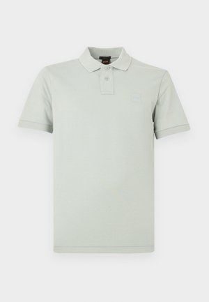 Ανοιχτοπράσινο πόλο πουκάμισο από βαμβάκι. Διαθέτει κλασικό γιακά, κούμπωμα με δύο κουμπιά και ένα μικρό λογότυπο στο στήθος. Κοντά μανίκια.