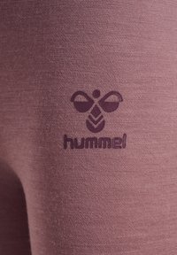 Paarse fabric leg van een broek met een gestructureerde afwerking en een donkerpaarse "hummel"-logo met een gestileerd bij-ontwerp.