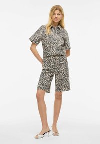 Kortermet skjorte med krage og matchende shorts i beige med svarte zebra-striper, laget av mykt stoff med en avslappet passform.