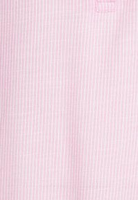 Tessuto rosa chiaro con sottili righe bianche, caratterizzato da una superficie liscia e una leggera lucentezza. Include un piccolo decoro ricamato sul bordo superiore.