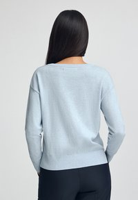 Ljusblå tröja med avslappnad passform, nedhasade axlar och ribbade detaljer i fållen. Mjuk textur med en minimalistisk design.