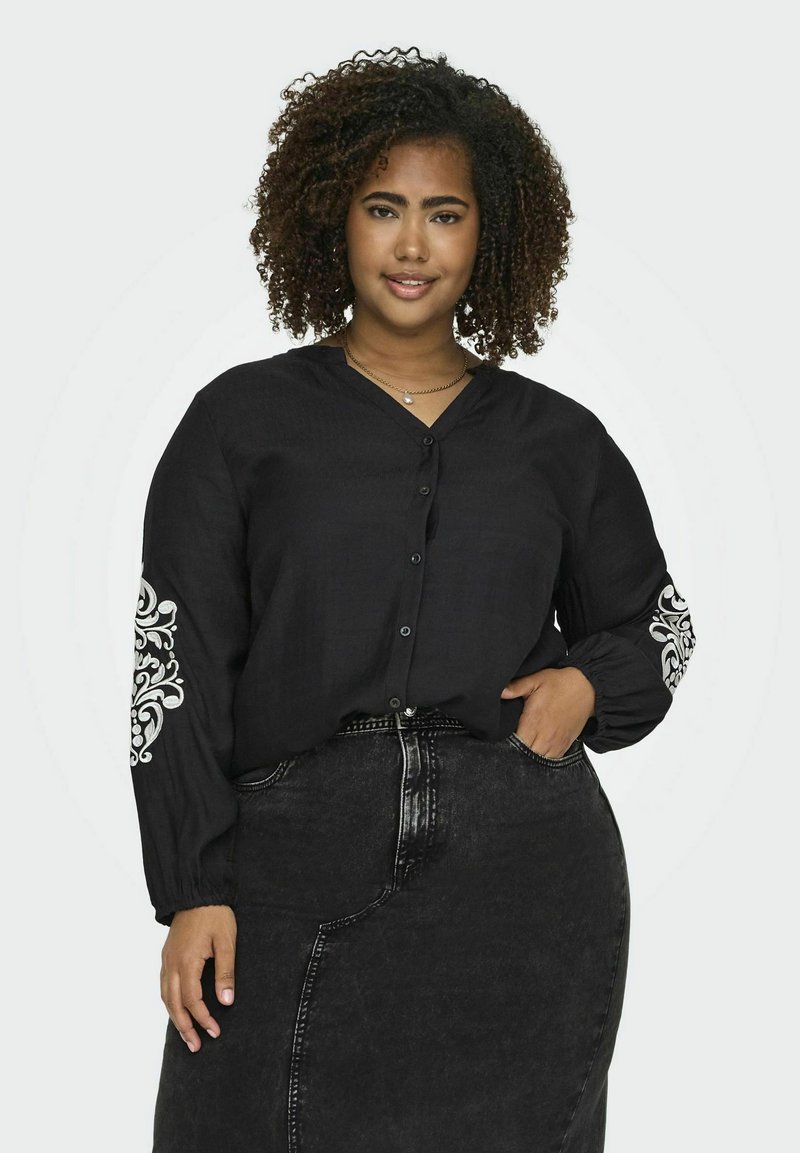 Cămașă neagră cu butoane, cu mâneci lungi, având motive decorative albe pe mâneci, asortată cu o fustă neagră din denim.