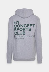 Harmaa huppari, jossa on kengurun tasku; takana on iso, tumma vihreä teksti, jossa lukee "NY CONCEPT SPORTS CLUB" ja sen alla on iskulause.