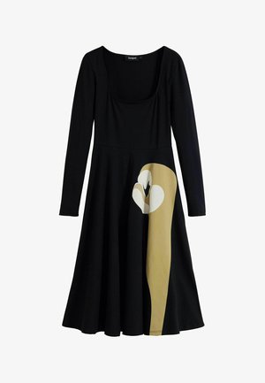 Svart långärmad klänning med figursydd överdel och utsvängd kjol; har en stor mönster av en krämfärgad och tan uggla på vänster sida.