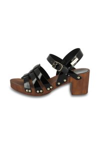 Sandalias de charol negro con un tacón de bloque de madera, que cuentan con múltiples correas cruzadas, tachuelas en tono dorado y un cierre de hebilla ajustable.