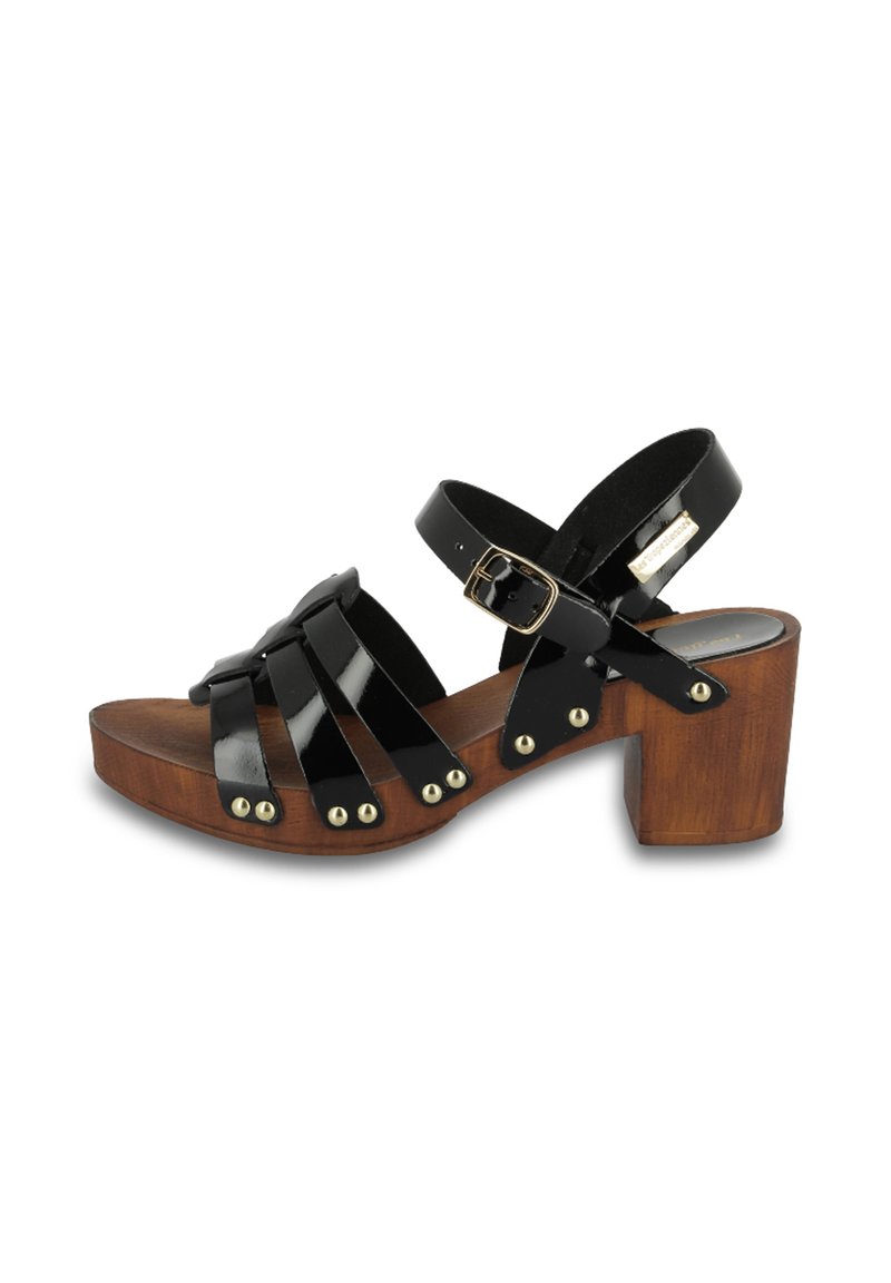 Sandalias de charol negro con un tacón de bloque de madera, que cuentan con múltiples correas cruzadas, tachuelas en tono dorado y un cierre de hebilla ajustable.