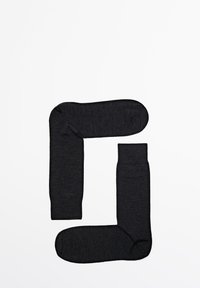 Schwarze, strukturierte Socken, die in Form eines 'G' angeordnet sind. Merkmale sind gerippte Bündchen und abgerundete Zehen, gefertigt aus einem weichen, dehnbaren Material.