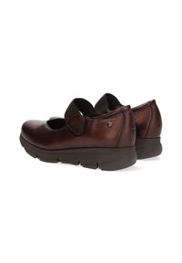 Zapatos de cuero marrón con un acabado texturizado, que cuentan con una correa ancha en la parte superior, suela acolchada y diseño de punta redonda.
