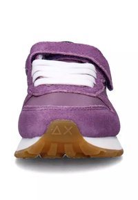 Sneaker viola in suede con lacci bianchi e fascetta in velcro. Suola intermedia bianca e suola in gomma. Punta arrotondata e superficie liscia.