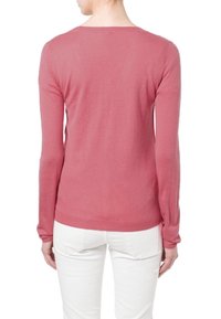 Langærmet sweater i blød lyserød strikning med rundet halsudskæring og ribbet kant, stylet med lyse bukser.