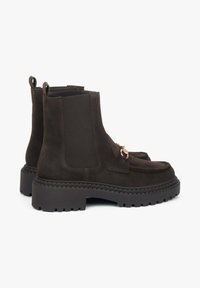 Brązowe zamszowe botki za kostkę z elastycznymi panelami po bokach, gumową podeszwą i złotym wykończeniem. Masywna konstrukcja z teksturowaną cholewką.