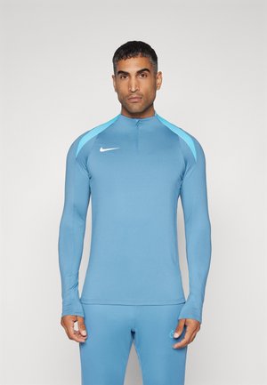 Lichtblauwe sporttop met lange mouwen en een half-rits kraag, met donkerblauwe schouderaccenten en een wit Nike-logo op de borst.