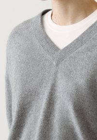 Gray wool v-neck sweater with a soft texture, layered over a white crew neck shirt. Features a classic design with ribbed trim.