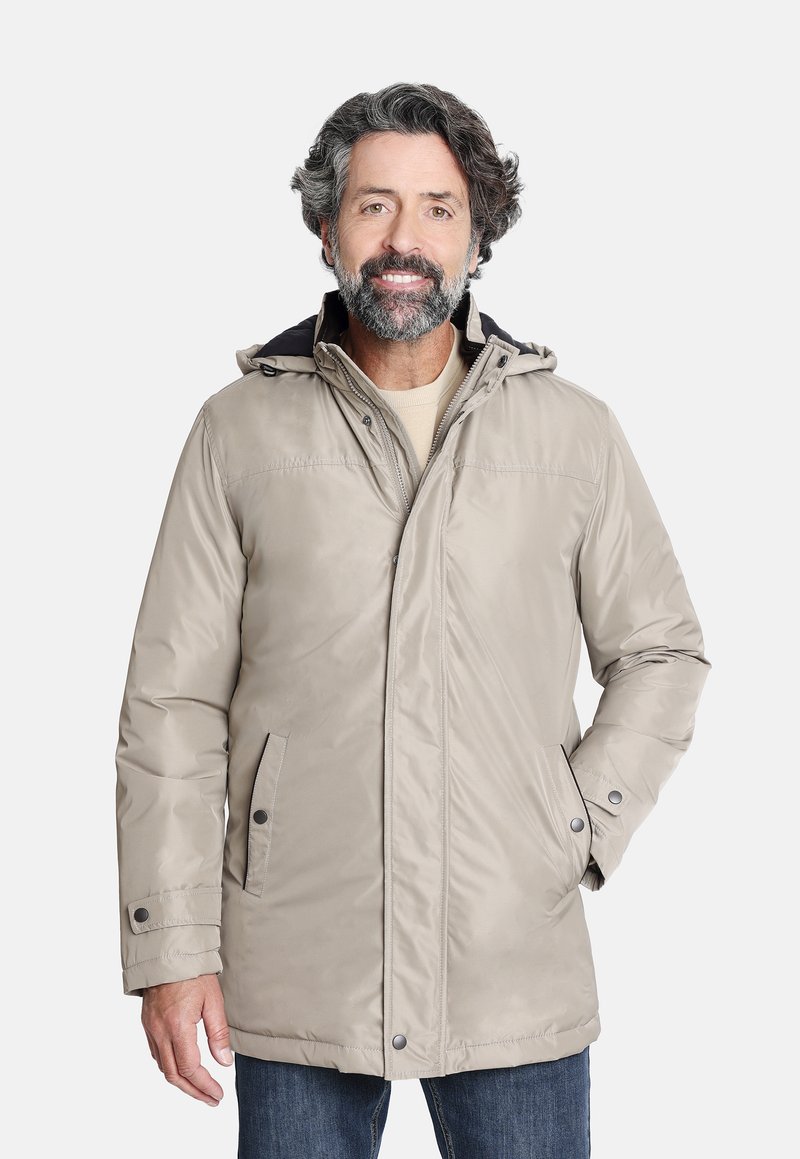 Parka impermeable beige con capucha, cierre frontal con cremallera, broches a presión y dos bolsillos laterales. La tela tiene una textura suave y mate.