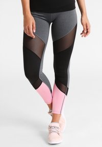 Leggings fitness con un design geometrico in grigio, nero e rosa, dotati di pannelli in rete traspirante e un tessuto fitted e elasticizzato.