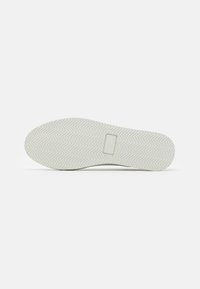 Suola di scarpa in gomma bianca con un motivo a spina di pesce e un accento rettangolare. Presenta una texture liscia e una forma arrotondata.