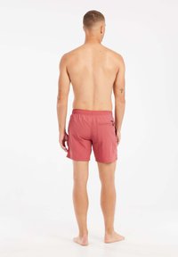 Bañadores para hombre en un color rosa apagado. Hechos de una tela ligera, con una cintura elástica y un bolsillo trasero con cremallera.