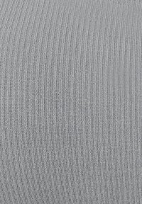 Detailní záběr na šedou vroubkovanou texturu látky s vertikálními pletenými vzory a jemnými detaily.