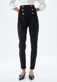 Hoge taille zwarte broek met een aansluitend ontwerp, voorzien van vier goudkleurige knopen en subtiele naaddetails. Glad textuur met een op maat gemaakte uitstraling.