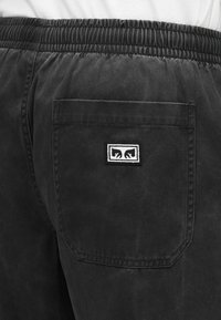 Μαύρο σορτς με ελαστική μέση, που διαθέτει πίσω τσέπη και ετικέτα με λευκό λογότυπο. Το ύφασμα έχει λεία υφή.