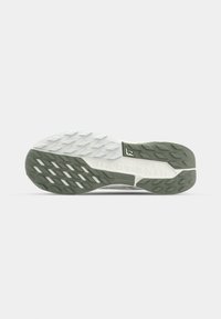 Shoe outsole featuring a green and white rubber design with textured traction patterns and a central logo accent.