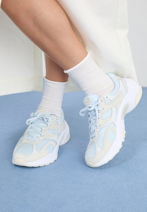 Light blue sneakers made of mesh and suede, with a chunky white sole, textured accents, and contrasting beige details.