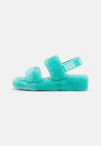 Tyrkysové nadýchané šlapky se dvěma silnými pásky a bočním pruhem se značkou. Měkká textura a obdélníkový tvar s plochou podrážkou.