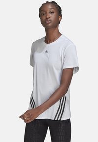 Camiseta blanca de manga corta con cuello redondo, que presenta el logo negro de Adidas en el pecho y tres rayas negras a los lados.