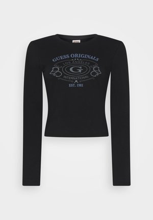 Camisa negra de manga larga hecha de tela suave, con un diseño gráfico central en gris que dice "GUESS ORIGINALS LOS ÁNGELES EST. 1981."