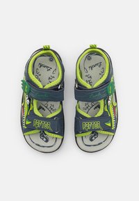 Blå sandaler med grønne detaljer, raptor-design og dinosaurgrafikk, justerbare stropper og teksturert fotseng for komfort. Størrelse 25.